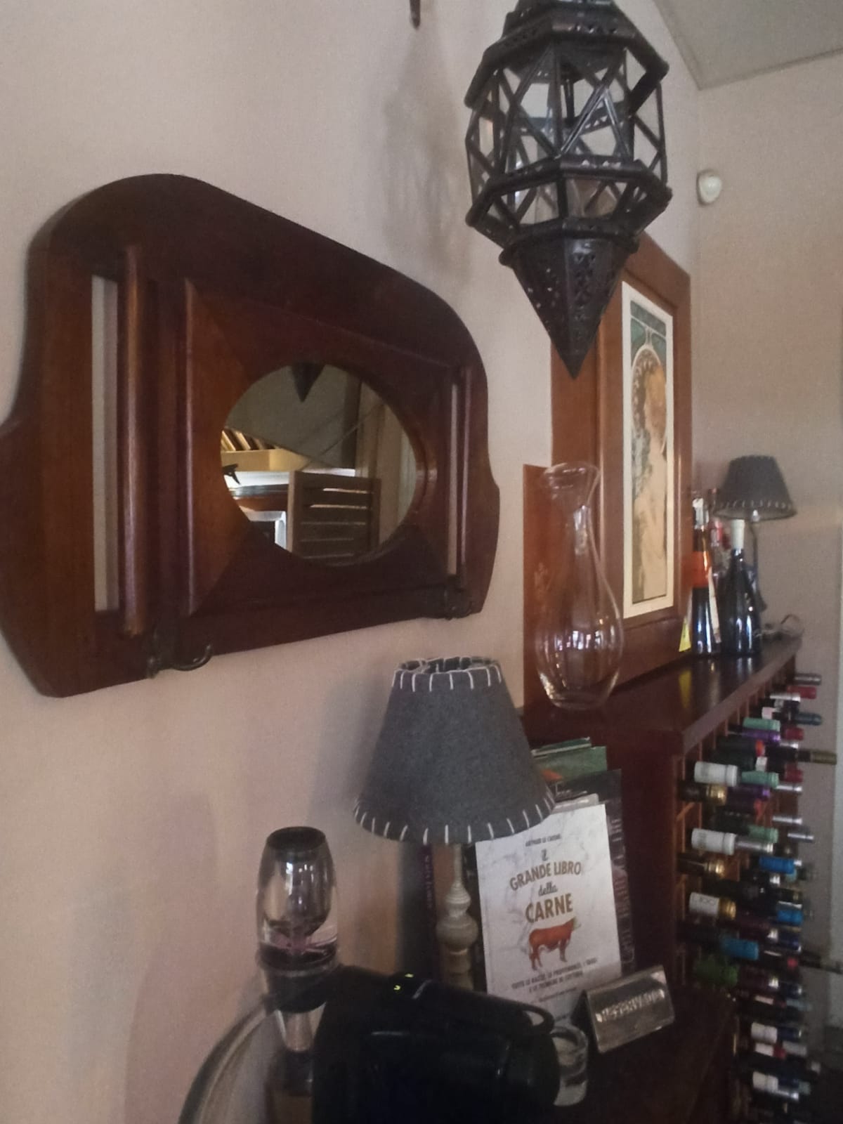 Rincón de la sala con espejo antiguo, farol marroquí y botellero de vino